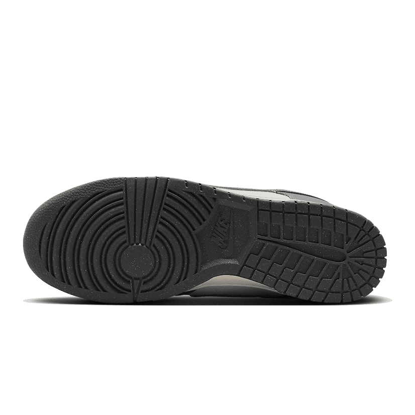 Sleek, grijze Nike Dunk Low Next Nature sneakers met een duurzaam, gerecycled ontwerp en een klassieke look op een donkere achtergrond.