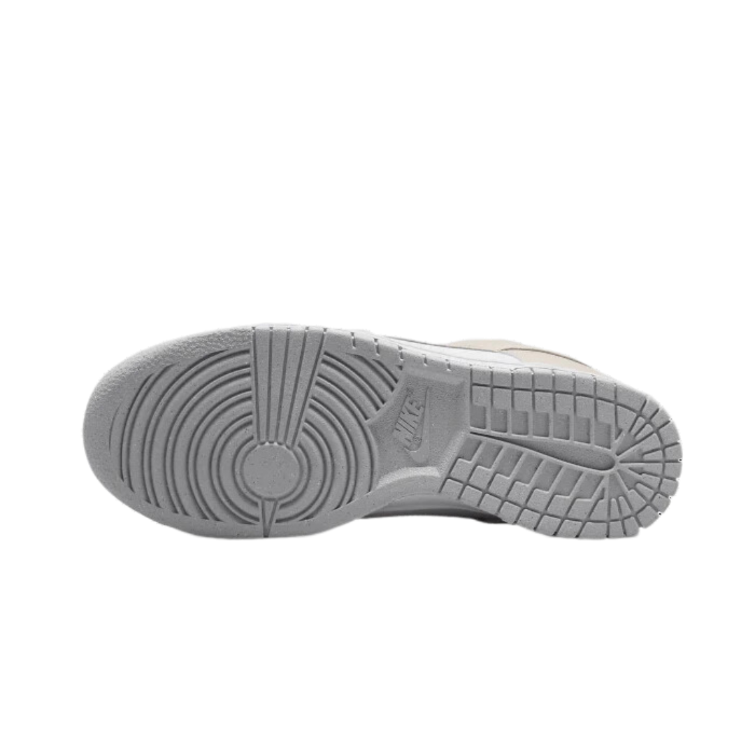 Klassieke witte Nike Dunk Low Next Nature sneakers met lichtbruine details en een solide rubberen zool op een zwarte achtergrond.