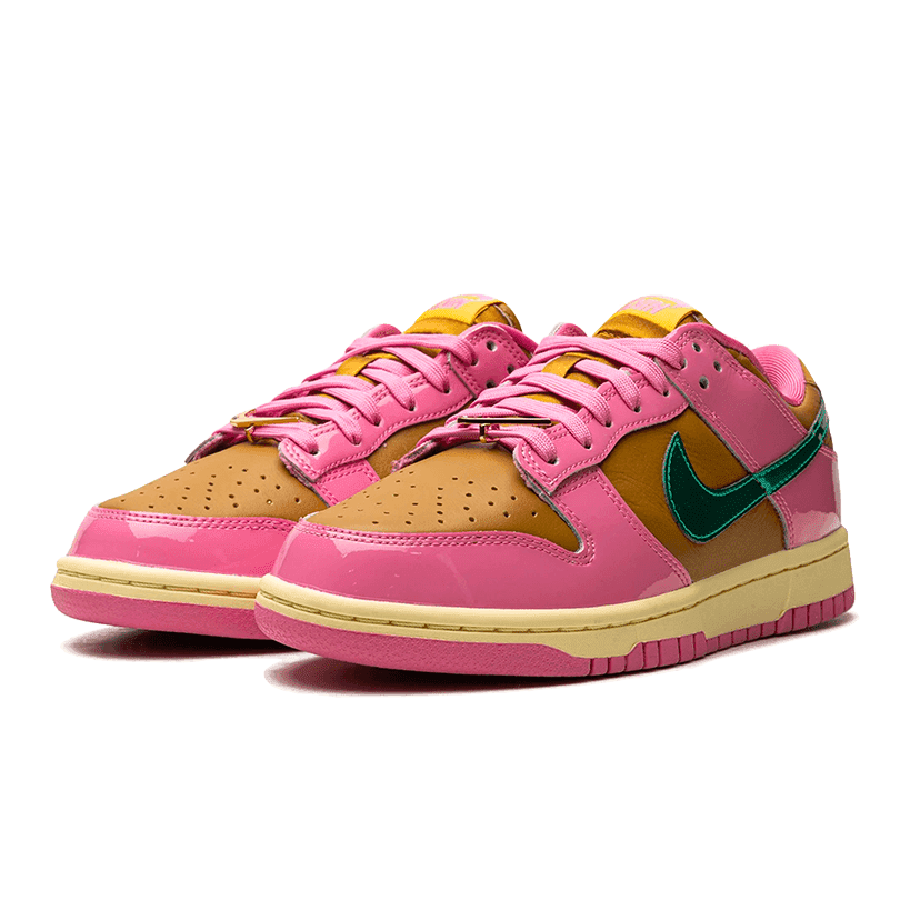 Roze Nike Dunk Low Parris Goebel sneakers met bruine en gouden accenten op een groen oppervlak
