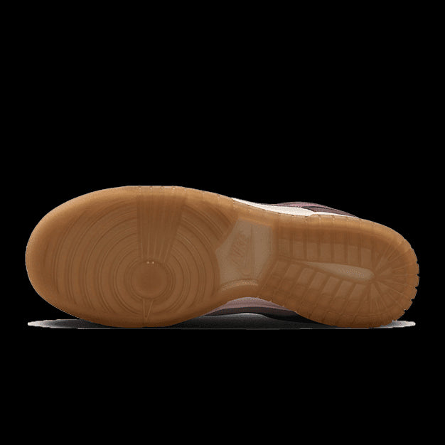 Elegante Nike Dunk Low Plum Eclipse-sneakers op een groene achtergrond. De zool van de schoen vertoont de houtnerf-textuur, terwijl de schoentop in een paars-bruine tint is uitgevoerd met subtiele perforaties voor ventilatie.