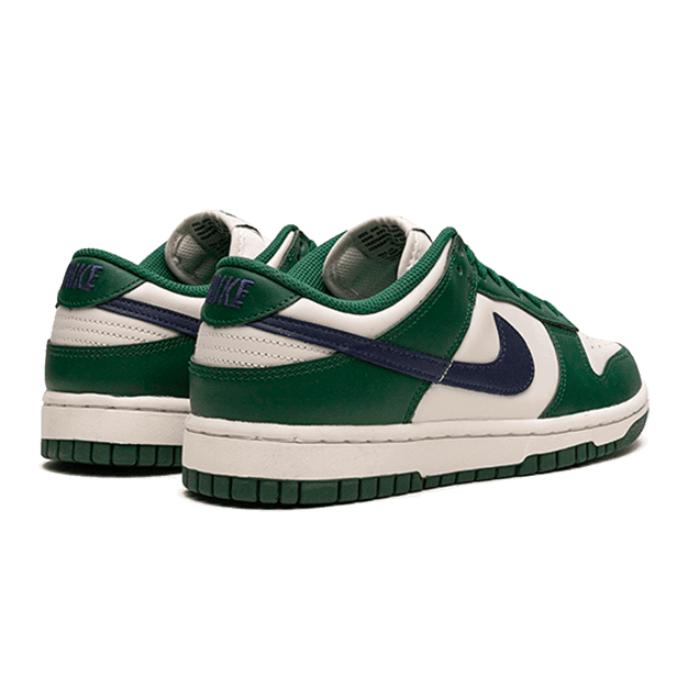 Stylvolle Nike Dunk Low Retro Gorge Green Midnight Navy sneakers op een groene achtergrond