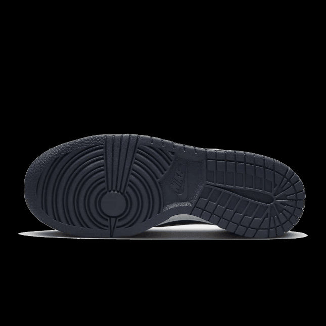 Zwarte Nike Dunk Low SE sneakers met een koperkleurige swoosh, op een effen groene achtergrond.
