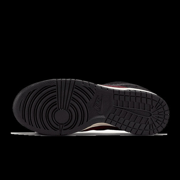 Burgund-rode Nike Dunk Low SE Fleece sneakers met een stevige rubberen zool op een groene achtergrond
