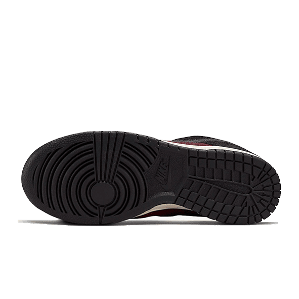 Burgund-rode Nike Dunk Low SE Fleece sneakers met een stevige rubberen zool op een groene achtergrond