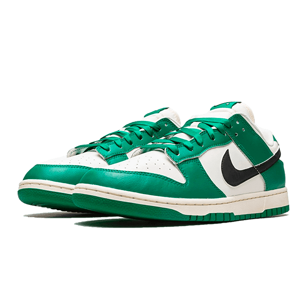 Groene en witte Nike Dunk Low SE Lottery sneakers op een groene achtergrond. Dit is een klassieke sneakerstijl met een contrasterende groene en witte kleursamenstelling. De sneakers hebben een opvallend ontwerp met stiksels en een Nike-logo, waardoor ze een stijlvol en sportief uiterlijk hebben.