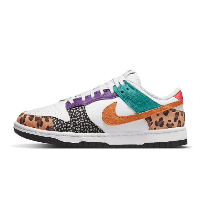 Trendy Nike Dunk Low Safari Mix sneakers met kleurrijke details op een groene achtergrond. De sneakers hebben een opvallende mix van dierenprint, lichtgekleurd materiaal en contrasterende accenten.