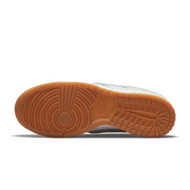 Sneakers met een opvallend rubberen zool in een zalmachtige tint, kenmerkend voor het Nike Dunk Low Scrap Sea Glass-model.