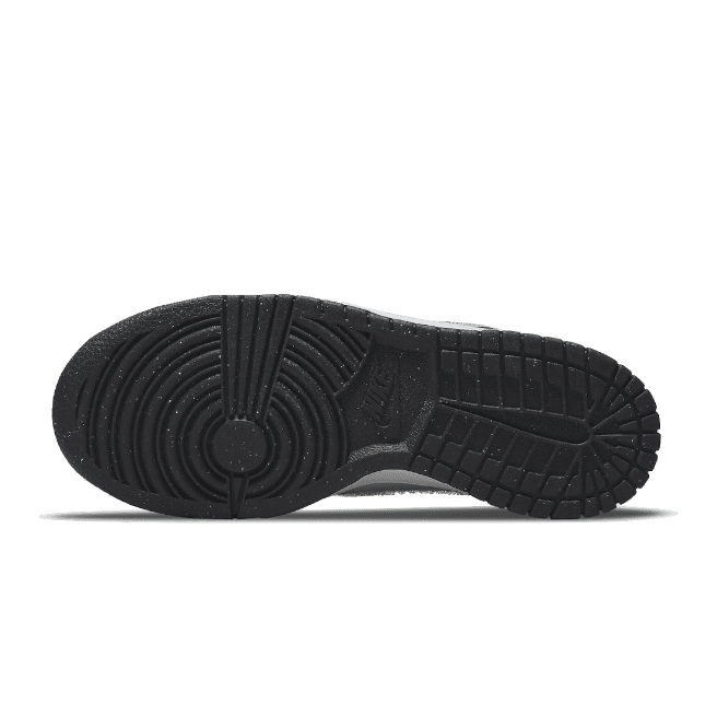 Zwarte Nike Dunk Low Signal Blue Lemon Twist sneakers met geribde zool op een groene achtergrond