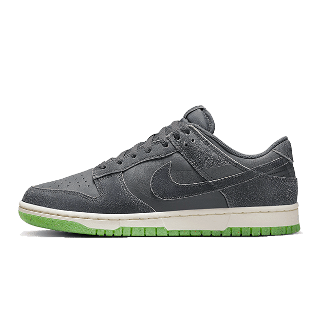 Nike Dunk Low Swoosh Shadow Iron Grey - Moderne grijze sneakers met de bekende Nike Swoosh op een groene achtergrond.