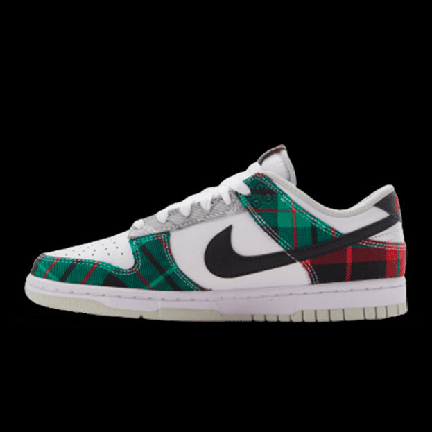 Nike Dunk Low Tartan Plaid sneakers op een groene achtergrond. De sneakers hebben een wit, zwart en groen geruit patroon en hebben de kenmerkende Nike-branding.