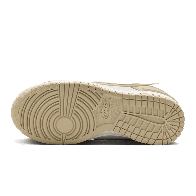 Beige Nike Dunk Low Twist Sanddrift sneakers met een markant zool profiel op een groene achtergrond.