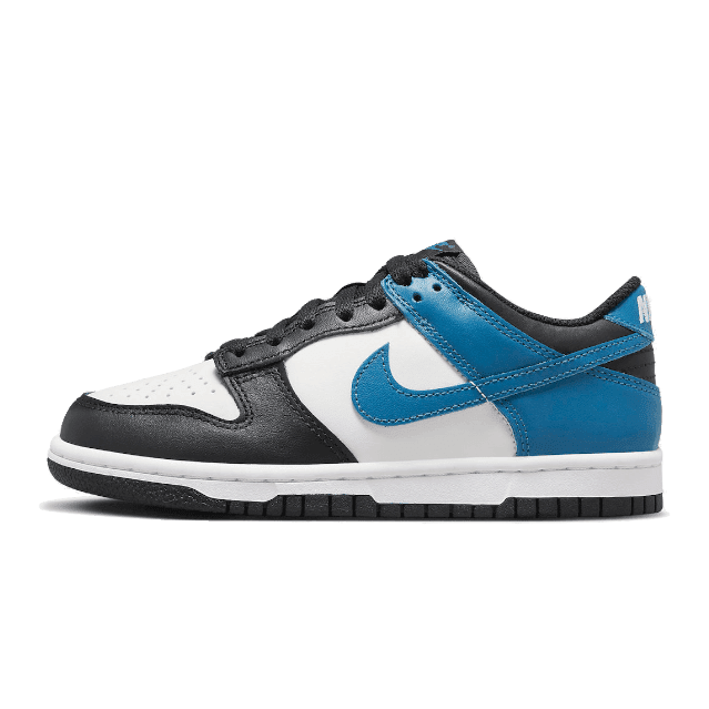 Witte, blauwe en zwarte Nike Dunk Low sneakers tegen een groene achtergrond