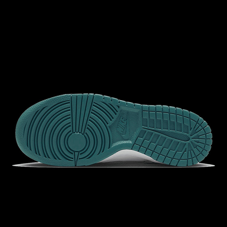 Klassieke Nike Dunk Low sneakers met witte, grijze en turquoise kleuren op een groene achtergrond