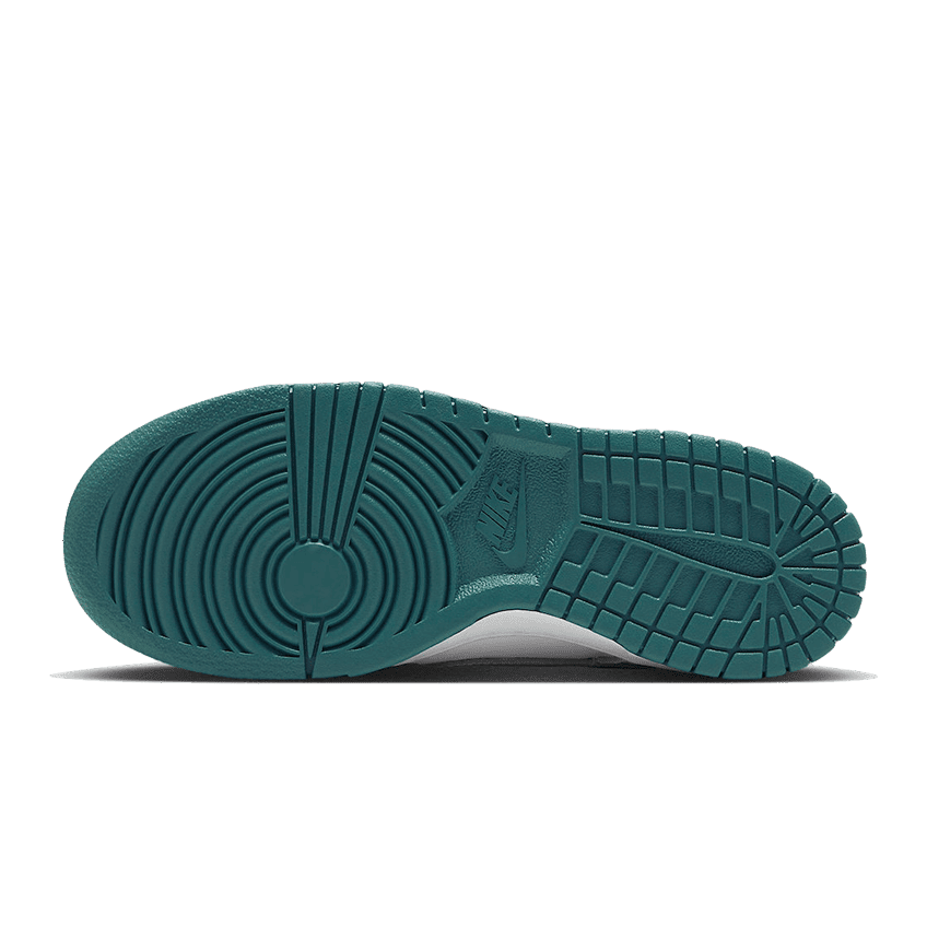 Klassieke Nike Dunk Low sneakers met witte, grijze en turquoise kleuren op een groene achtergrond