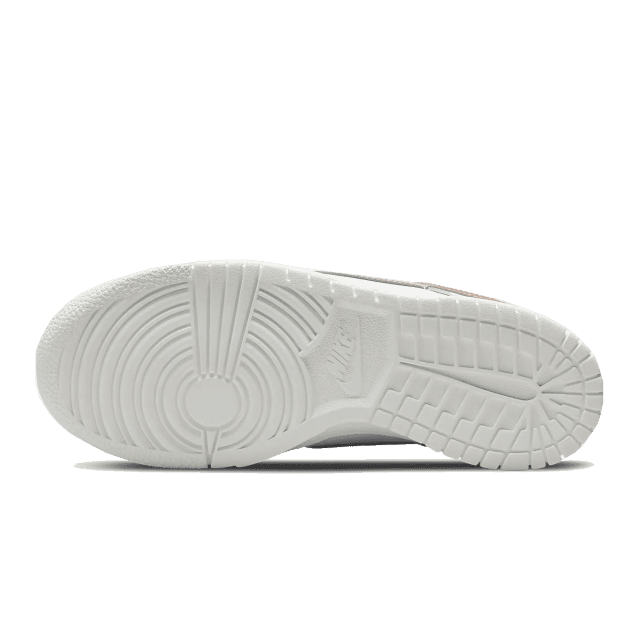 Witte lage sneakers met roze details van Nike op een groene achtergrond