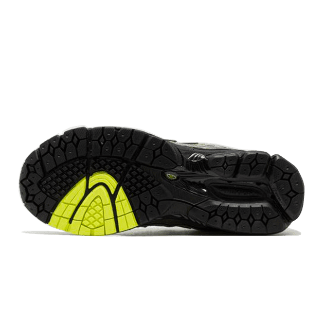 Stijlvolle New Balance 1906R Volt Black sneakers op groen oppervlak